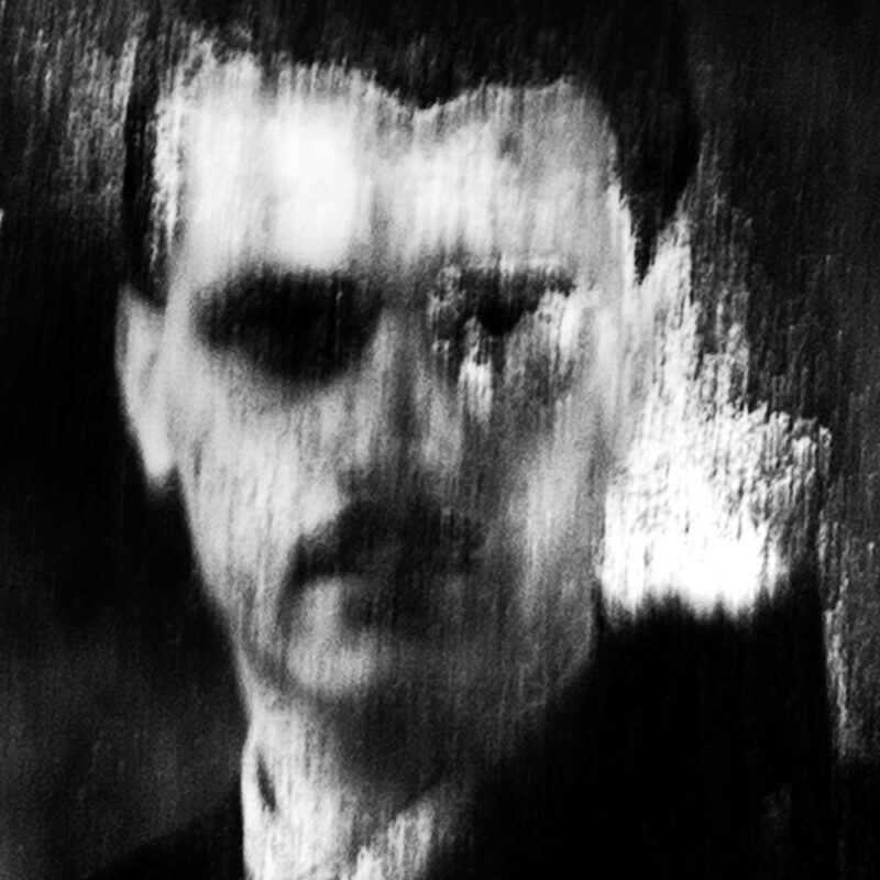 Worn black and white portrait of a man evoking memory and erosion of identity by Eleni Onasoglou.