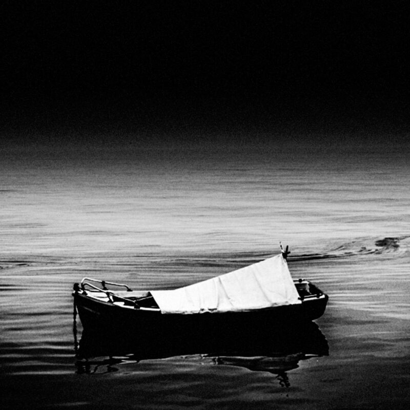 Black and white fine art photograph of a boat in a quiet seascape by Eleni Onasoglou.
