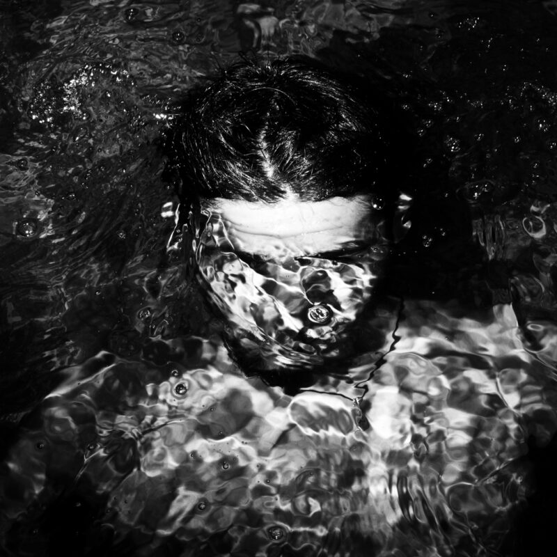 Black and white fine art photograph of a boy underwater exploring silence and suspension by Eleni Onasoglou.